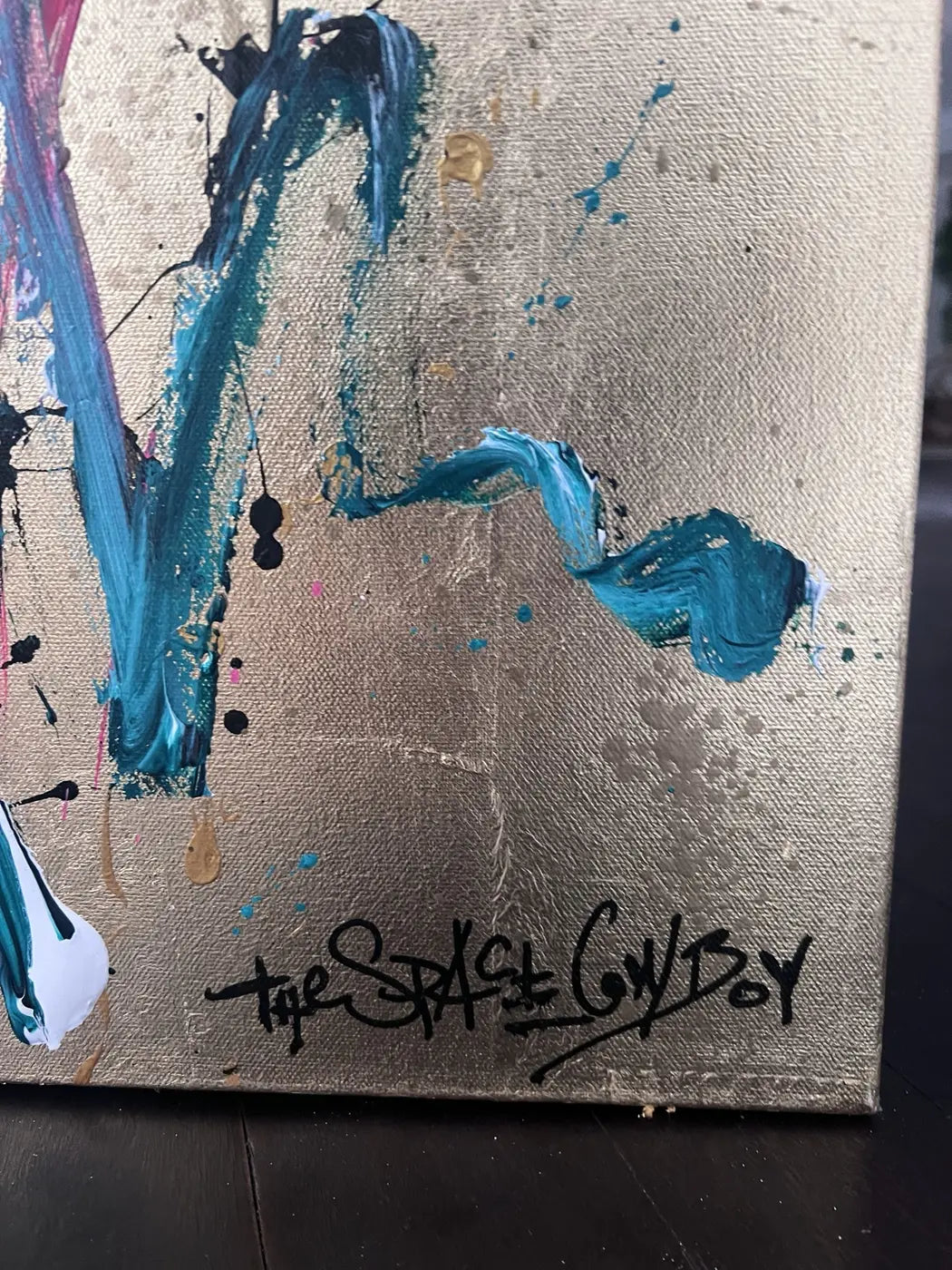 Close-up of The Space Cowboy’s signature over the textured gold ground of Never too late – Party time.
