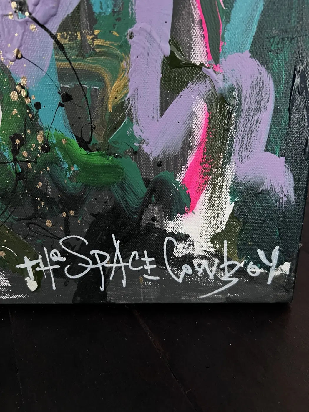 Close-up of The Space Cowboy’s signature beside layered green, lilac, pink and black marks.